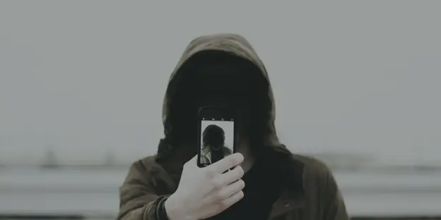 man in hoodie taking a selfie