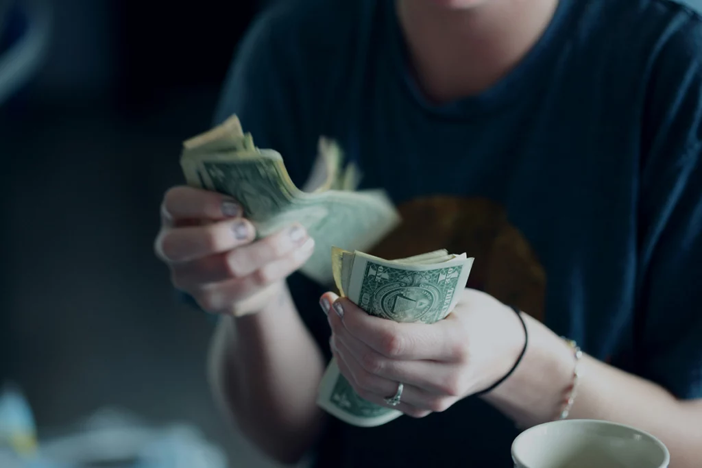 Image shows a pair of hands holding currency notes 