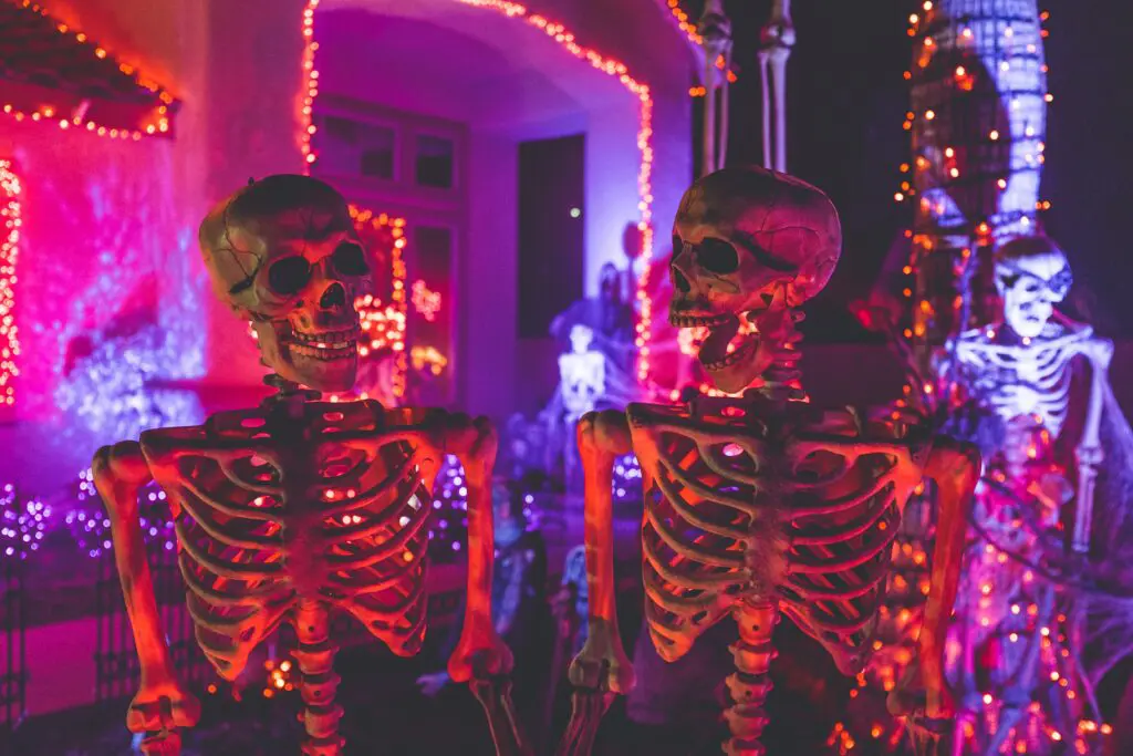 two halloween skeleton decorations facing each other in front of decorated house
