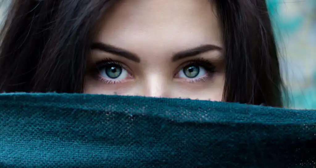 woman peeking over blanket