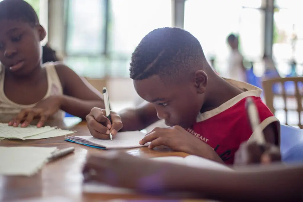 child writing on paper in school