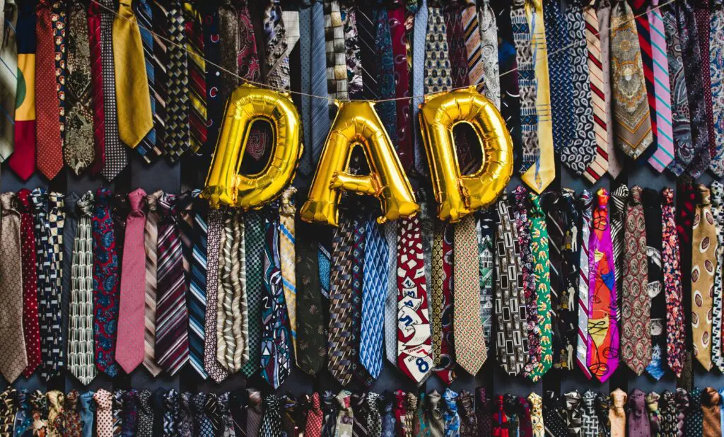 Balloons that spell out "dad" in front of closet with ties