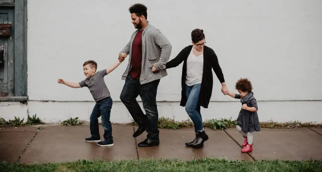 family holding hands and walking down sidewalk