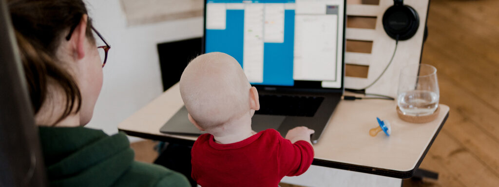woman holding baby in lap while baby messes with laptop
