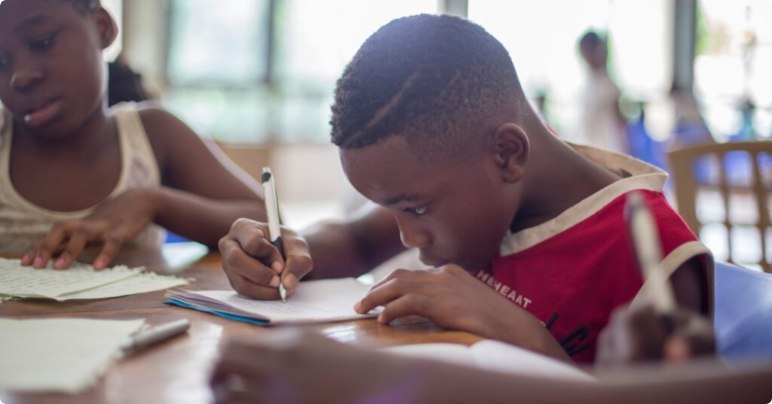boy writing on notepad in classroom
