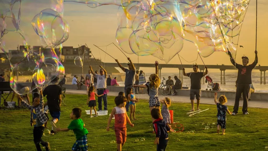 Several adults and children playing outdoors with bubbles of various sizes=