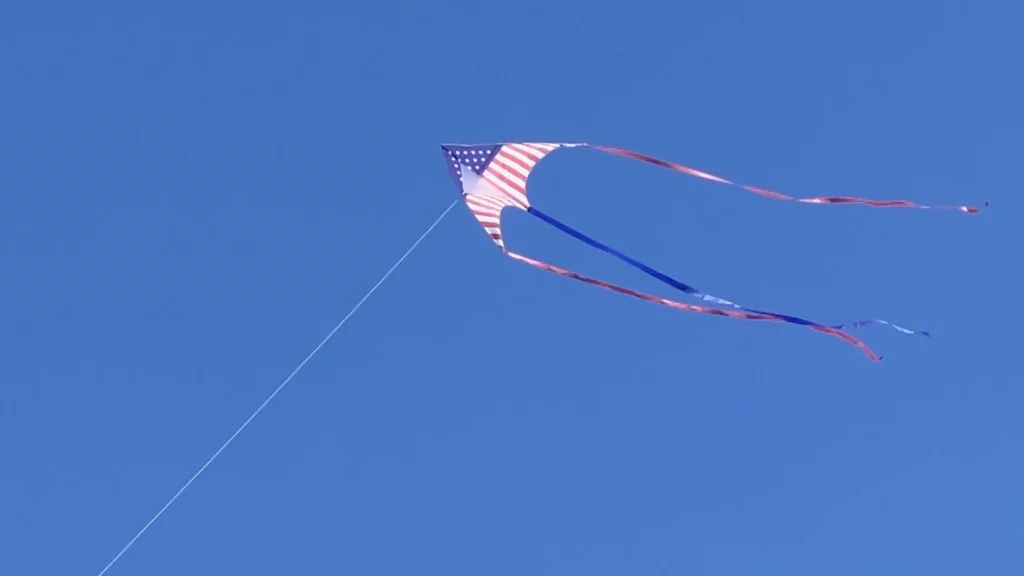 Red, white, and blue flag flying against a cloudless sky.