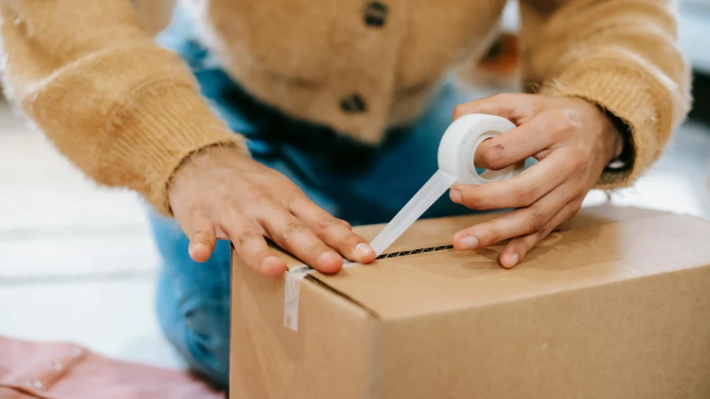 Person closing a care package with tape. They’ll send the package to active-duty military personnel.
