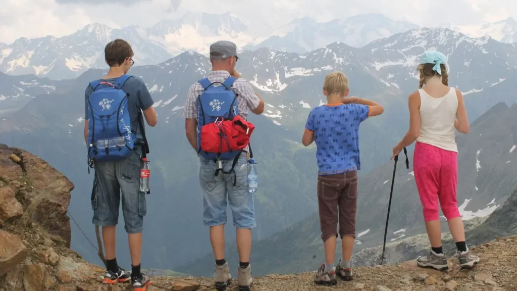 Back view of four people looking at mountains from a cliff.