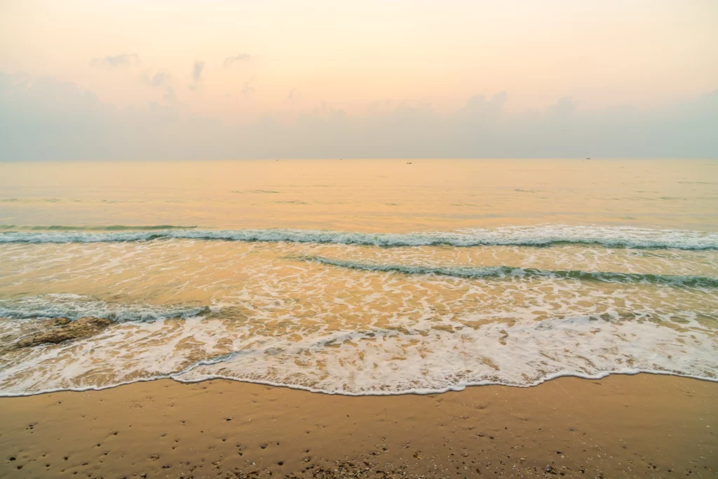 Snapshot of frothy water waves meeting the sand as one enjoys cheap beach vacations