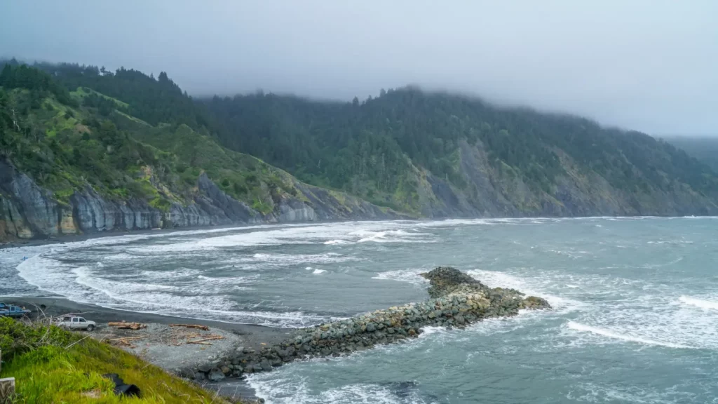 Snapshot of the California Shelter Cove beach with a rocky ridge along with hilly areas along the coastline represents what could be cheap beach vacations for many people.