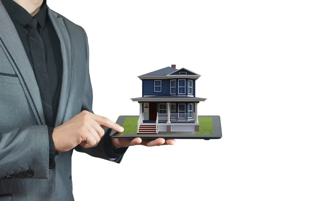 Torso of a real estate agent wearing a black shirt, black tie, and gray coat holds a tablet in one hand while touching the screen with the other and a model of a two-story home sits on the tablet.