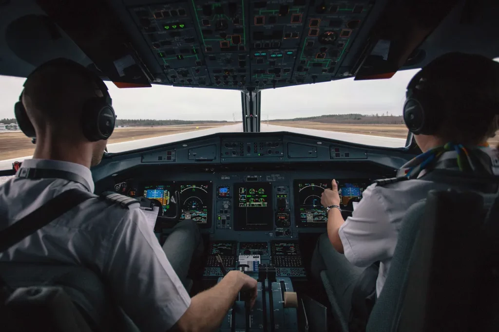 Image captures the cockpit of an aircraft along with two commercial pilots.