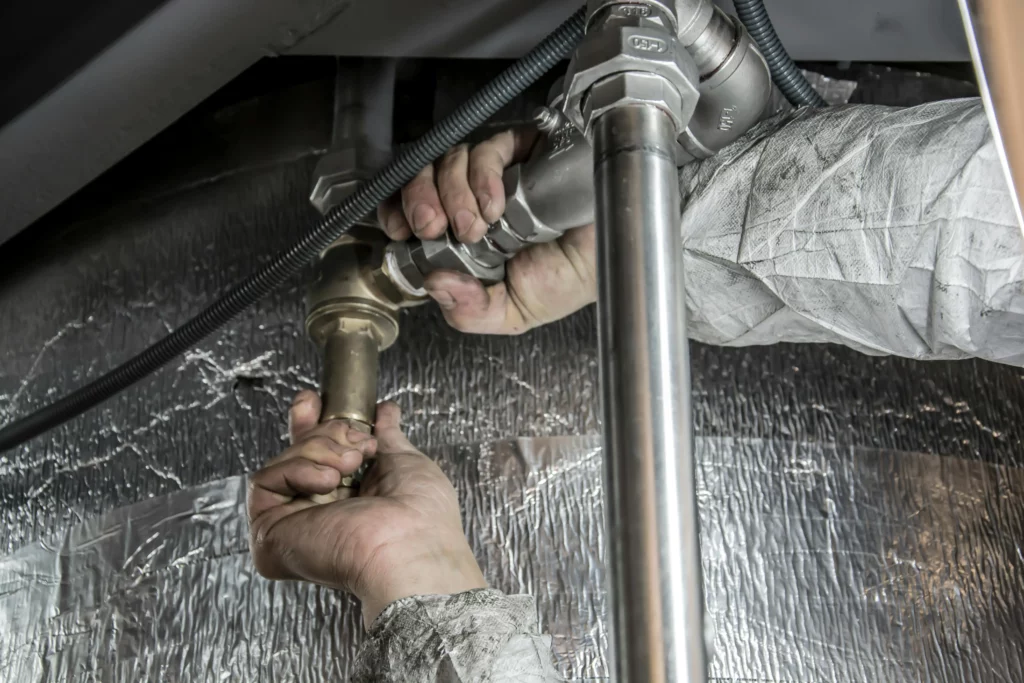 Image of a plumber using their two hands to work with and repair pipes