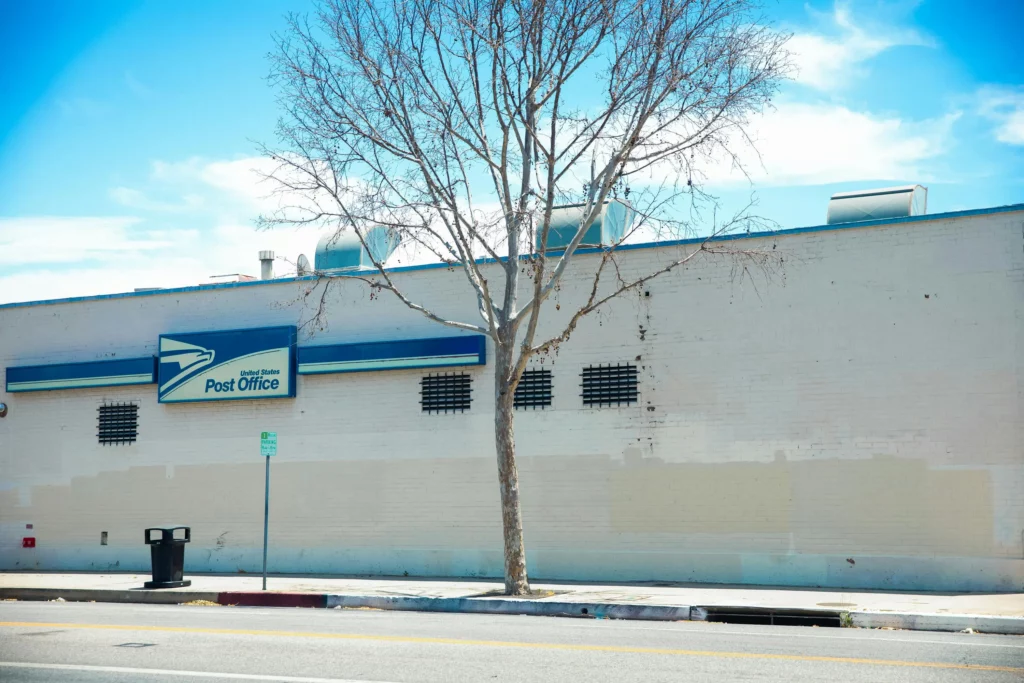 Image of a white building with a United States Post Office sign mounted on it.